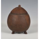 An early 20th century coconut shell tobacco box, polished finish with short tripod feet, the domed