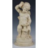 A reconstituted marble winged figure of Cupid, 20th century, seated on a tree stump with flowers