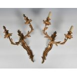 A pair of French gilt metal foliate cast wall lights, in a rococo style, each having twin