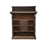 A Victorian carved oak open bookcase, the raised back with floral and Green Man carving over a