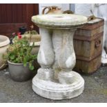 A composite stone plinth, of circular form with three integral baluster columns, 23in. (58.5cm.)
