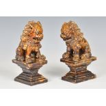 A pair of Chinese treacle glazed temple guardian lions, probably 19th century, seated upon waisted