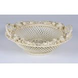 An Irish Belleek pierced circular basket with iridescent glaze, twin double handles, clover leaves