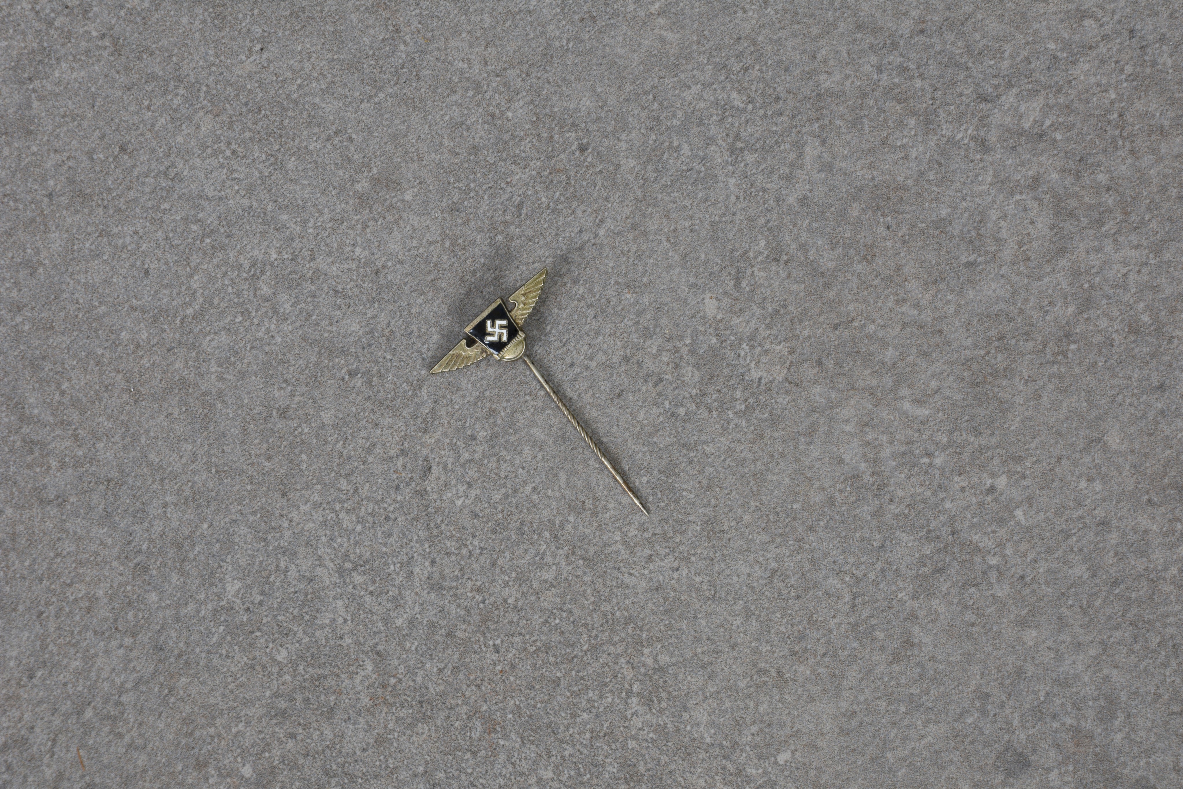 A German WWII S A Reserve stickpin enamel swastika between wings on the knurled pin, the reverse