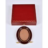 A Cartier 'Les Must de Cartier' oval photograph framein maroon enamel, the signed, gilt metal