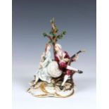 A Capodimonte figure of a courting couple in 18th century costume, seated beneath a tree, the