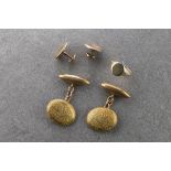 A pair of antique 15ct gold cufflinks the domed oval faces chased with leafy scrolls, marked '15CT',