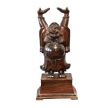 A large Oriental carved hardwood statue of a laughing buddha with his arms raised standing on a