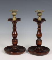 A pair of turned wood candlesticks with brass sconces