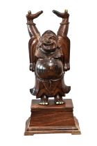 A large Oriental carved hardwood statue of a laughing buddha with his arms raised