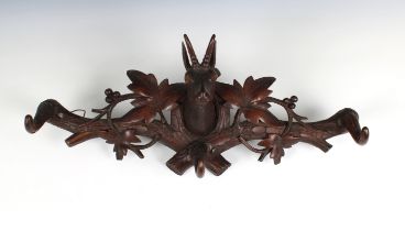 A carved oak wall mounted pair of coat hooks flanking a deer's head