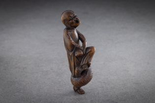 A GOOD WOOD NETSUKE OF A SENNIN (immortal or sage) STANDING ON ONE LEG