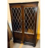 An Ercol modern display cabinet/bookcase with double leaded glass doors over linen fold panel doors
