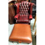 A modern red leather wing back arm chair with deep button back and a large brown leather effect foot