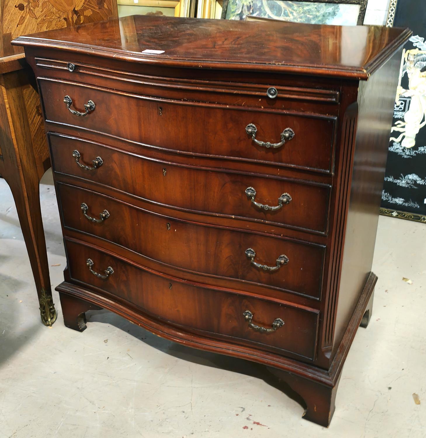 A reproduction mahogany bachelors chest with serpentine front, brushing slide and 4 graduating