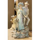 A 19th century, coloured bisque courting couple with a dog, standing on rocks. height 43cm