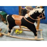 A modern rocking horse, black fur effect body, cream wool mane and tail with leather effect saddle