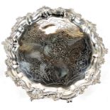 A circular Georgian hallmarked silver salver with scroll and acanthus border and chased centre, on 3