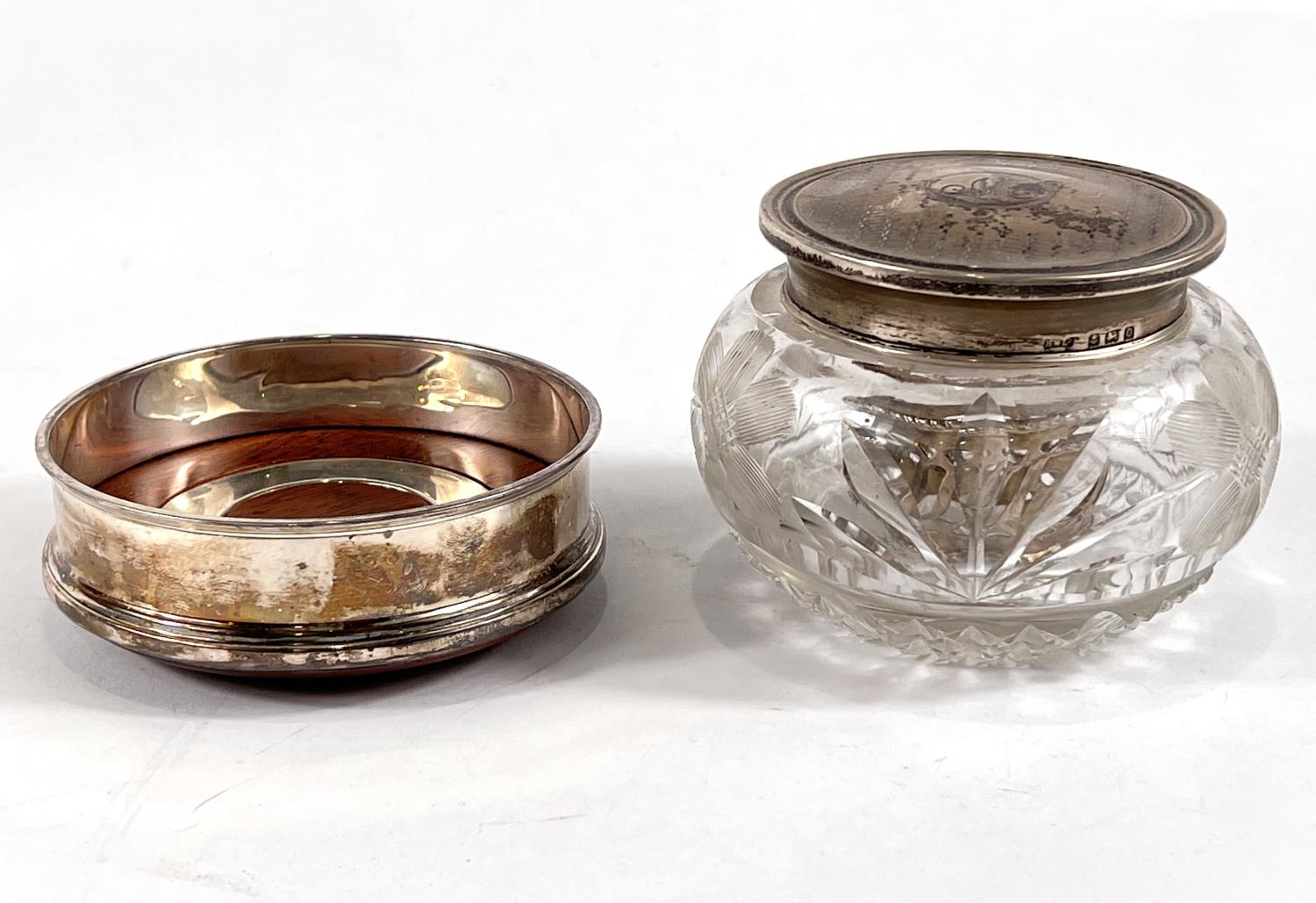 A hallmarked silver coaster by Cars, a silver lidded cut glass trinket jar and a napkin ring