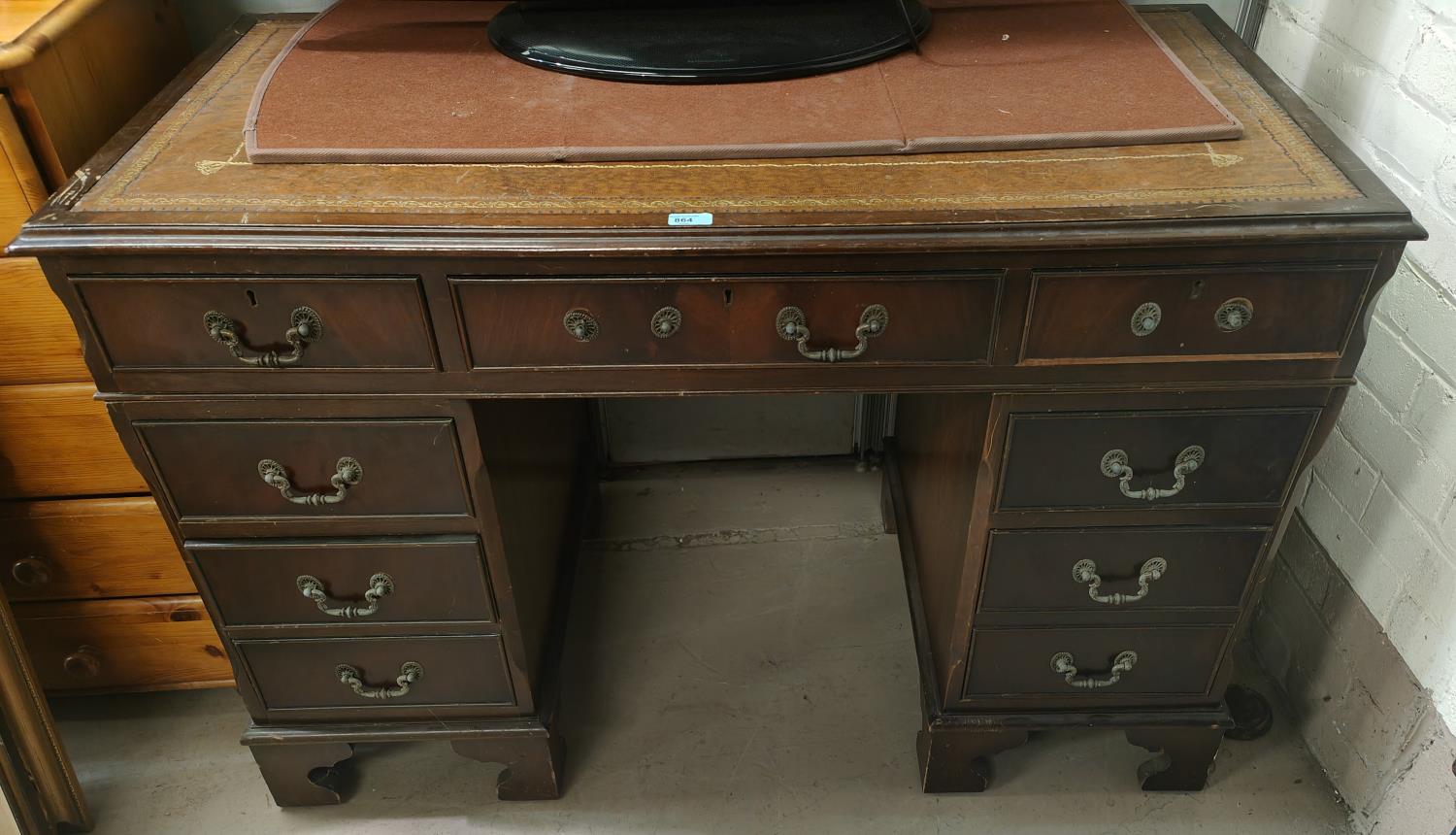 A mahogany desk with green writing insert, three drawers to each pillar and a central draw