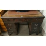 A mahogany desk with green writing insert, three drawers to each pillar and a central draw