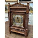 A late 19th/early 20th century architectural oak carved bracket clock with brass dial, silver