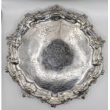 A circular Georgian hallmarked silver salver with scroll and acanthus border and chased centre, on 3