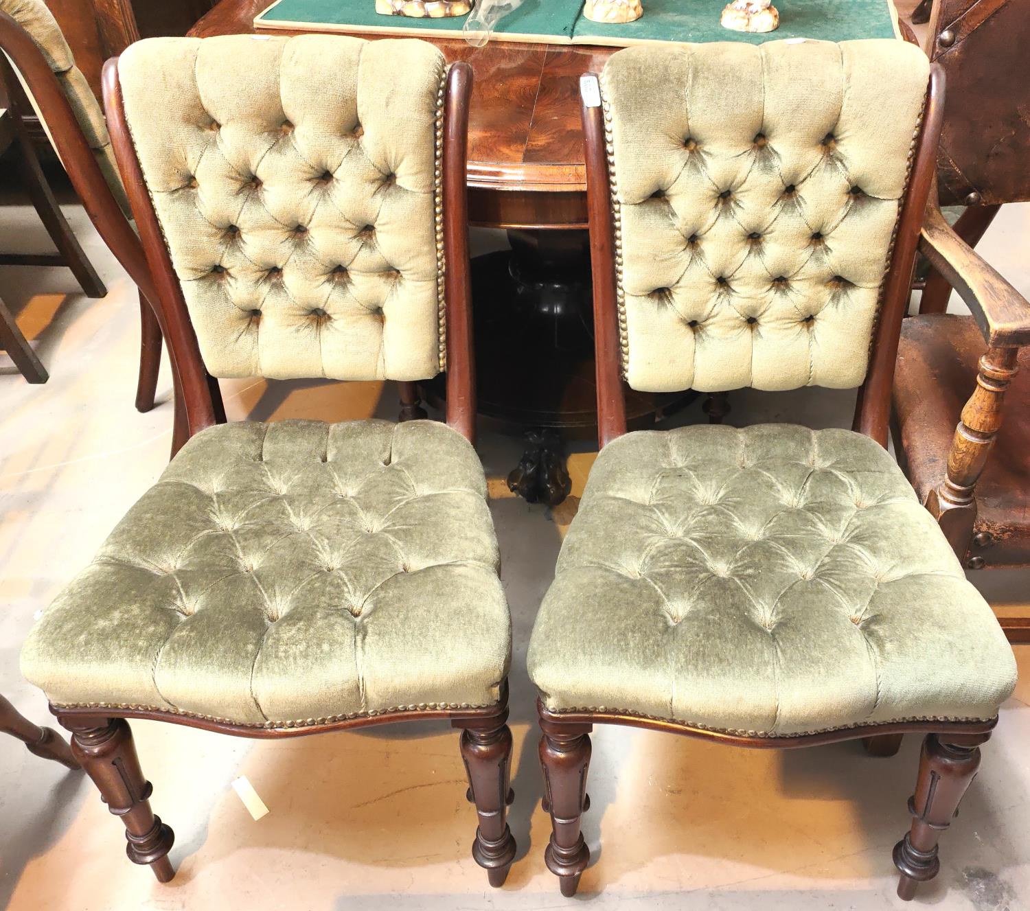 A set of six early 19th century dining chairs with deeply button back green upholstery, carved