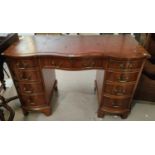 A reproduction pedestal kneehole desk in yew wood, with inset red leather top, frieze drawer and 8