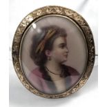 A miniature bust portrait on porcelain brooch of a young lady in 18th century dress in yellow