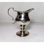 A  Georgian style classical helmet shaped hallmarked silver cream jug on pedestal base. London 1816,