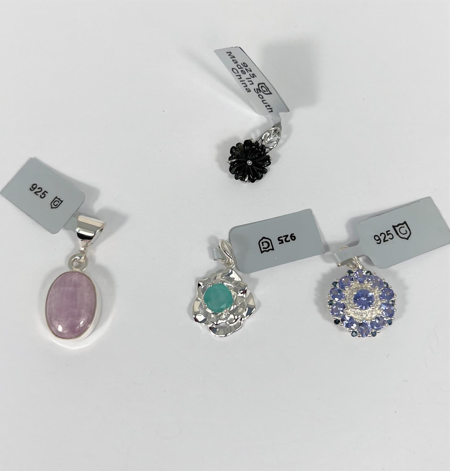 A selection of sterling silver pendant drops to include a circular tanzanite blue sapphire and white