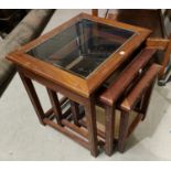 A nest of three glass top occasional tables