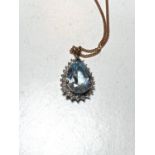 An 9ct hallmarked gold pendant set with a teardrop shaped aquamarine coloured stone surrounded by