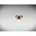 A 18ct hallmarked gold ring set with a central emerald cut ruby surrounded by 14 diamonds.