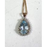 An 9ct hallmarked gold pendant set with a teardrop shaped aquamarine coloured stone surrounded by