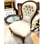 A Victorian mahogany spoon back nursing chair on knurled feet and castors in buttoned fawn fabric