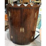 An 18th century oak bow front cupboard enclosed by 2 doors