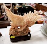 A large cream and brown soapstone depicting a sea eagle diving for a fish on brown ceramic base