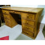 A modern stripped pine desk of eight pedestal drawers with one central drawer, length 141cm, depth