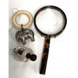 A vintage tortoise shell effect magnifying glass, a silver and mother of pearl rattle/ teething ring