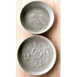 Two Chinese green glazed dishes with relief decorated scenes to base of dishes, diameter 22cm and