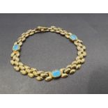 A yellow metal multi link bracelet with 3 inset turquoise stones stamped Flora 22k, 9.9gm