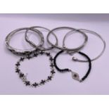 4 silver bangles and 2 bracelets set with black and clear stones, one with 2 red stones