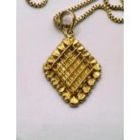 A gold diamond shaped pendant with raised cross hatch decoration stamped '22k', 3.6gms (with gilt