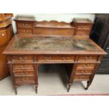 An Edwardian oak kneehole desk with raised back, frieze drawer and 8 pedestal drawers