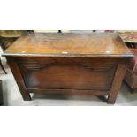 A 1930's oak blanket box with hinged lid and relief decoration to the front