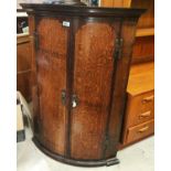 A Georgian oak bow front corner cupboard with mahogany cross banding