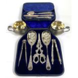 An ornate set comprising berry spoons, nutcrackers and grape scissors, cased; a hallmarked silver