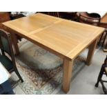 A modern light oak dining table with extending rectangular top